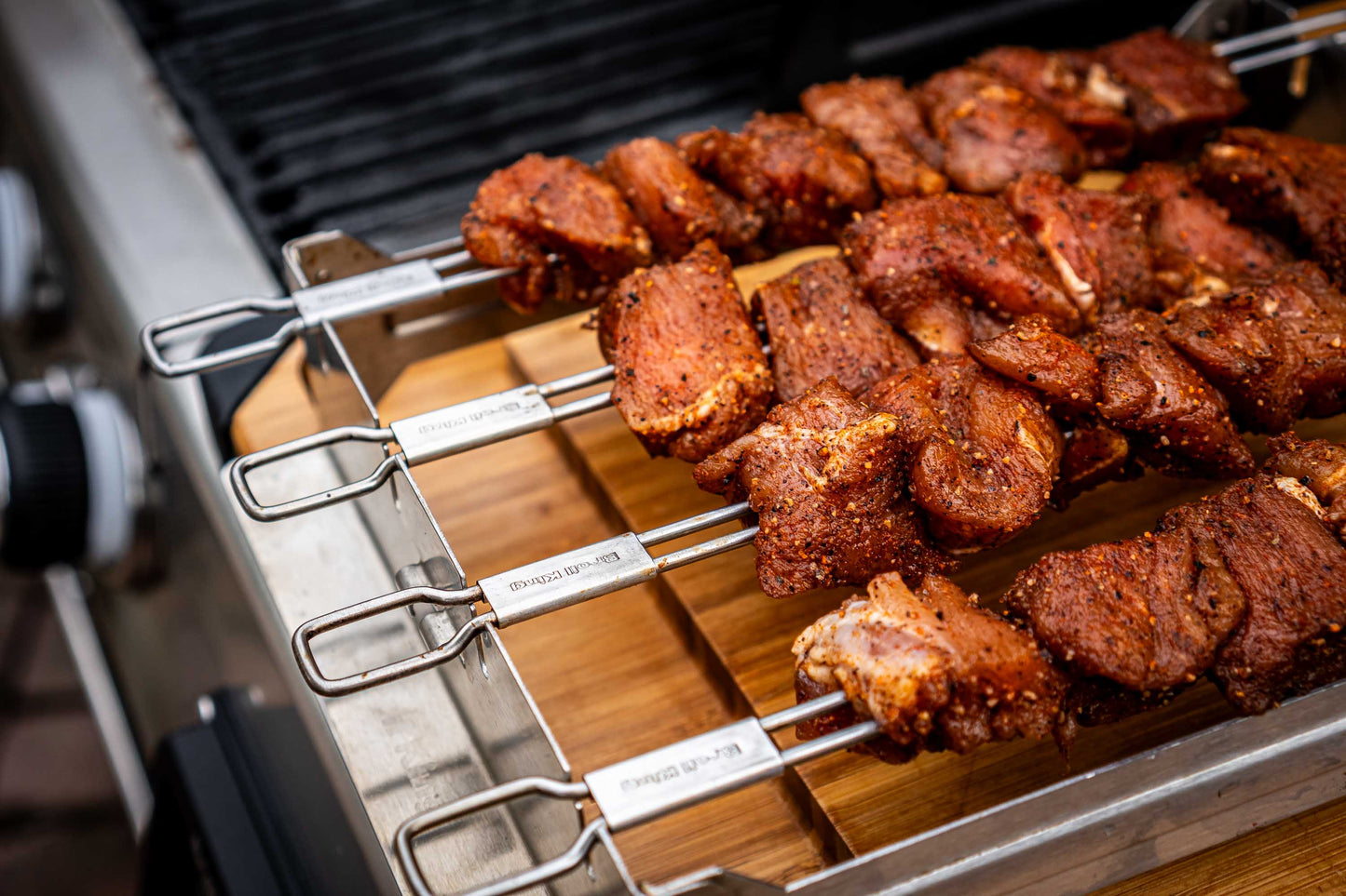 Skewered meat on a grill with a wooden board